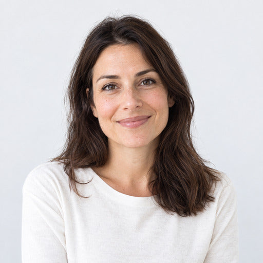 Portrait d une femme adulte en buste, cheveux bruns mi-longs, haut ecru uni, sur fond gris tres clair uni